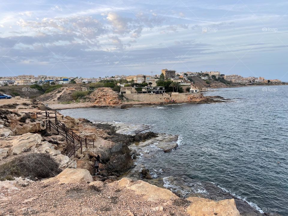 Rocky beach promenade with local flora towards sunset, Torrevieja Spain 