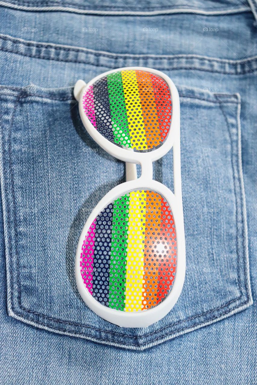 Rainbow glasses in jeans pocket