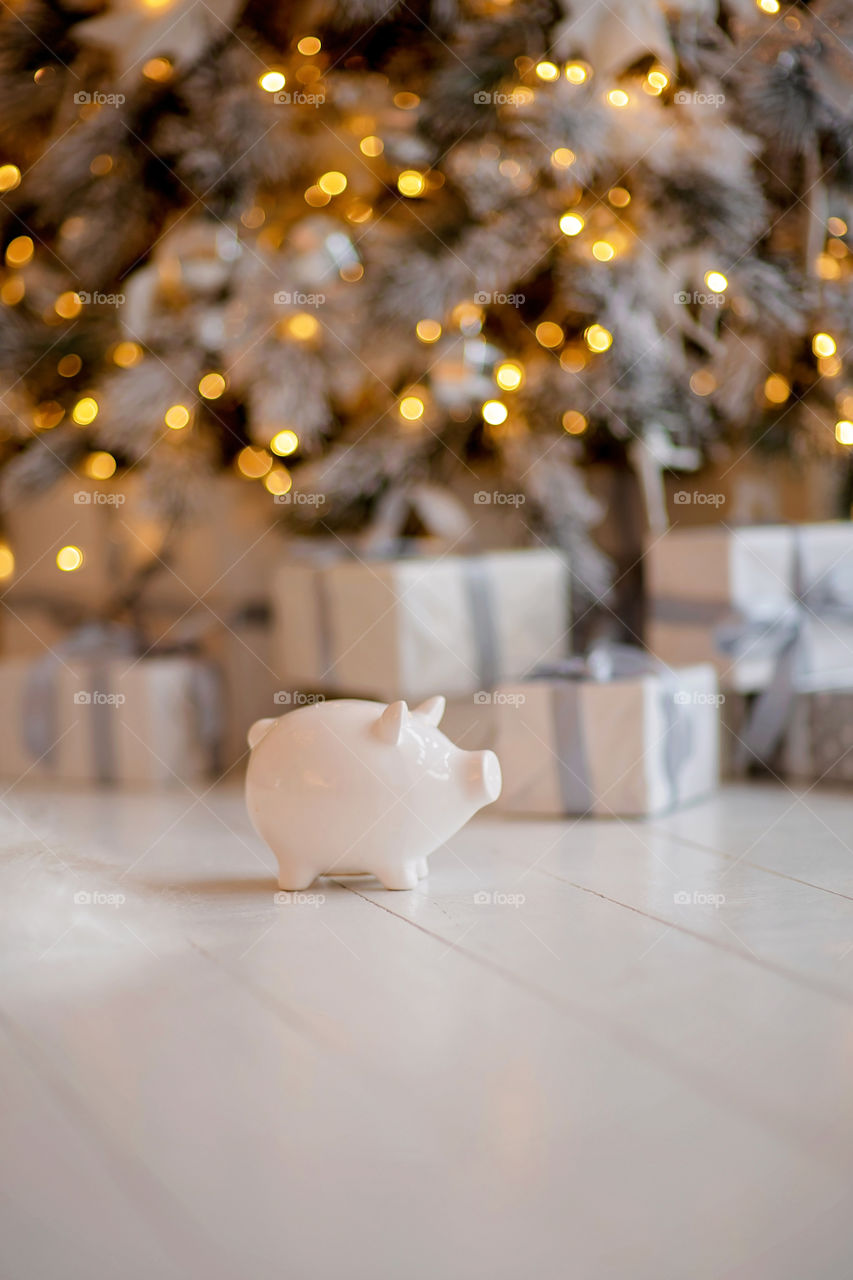 piggy bank with 100 dollars banknote in festive New Year atmosphere of scenery.  Magical bokeh with Christmas tree and bright lights.