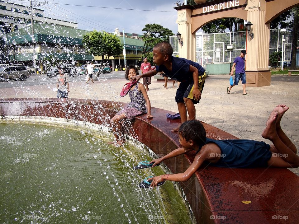 young kids playing at a water fountain