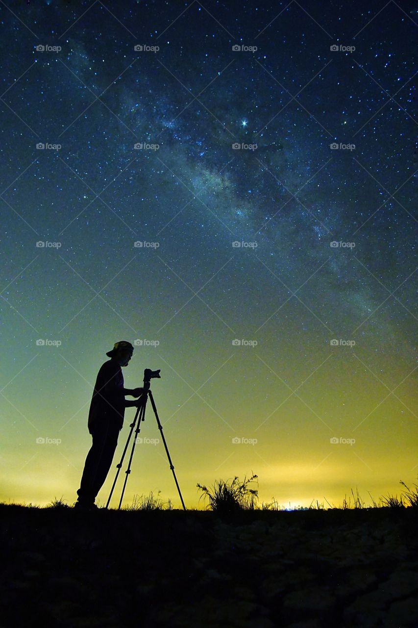 Night sky with stars and silhoutte of a standing happy man.