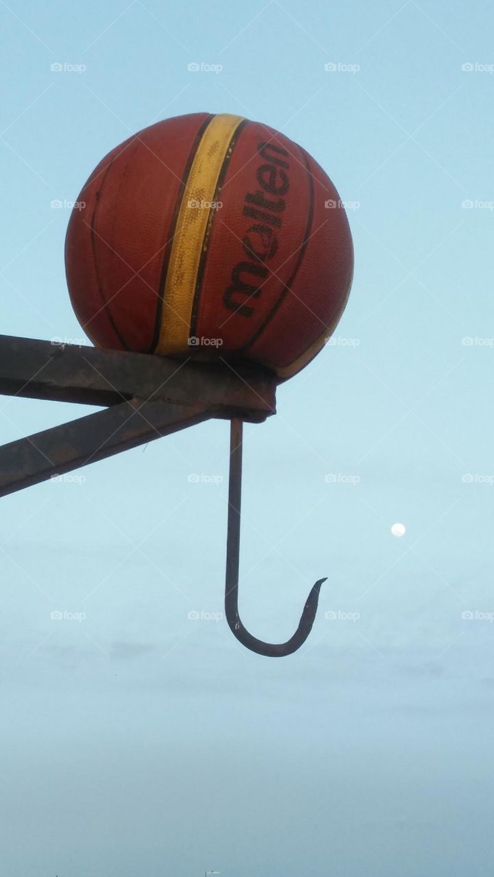  A ball hugging the moon in blue sky.