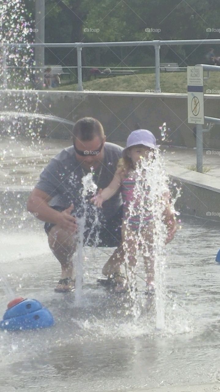 Dad and daughter playing at the splash pad