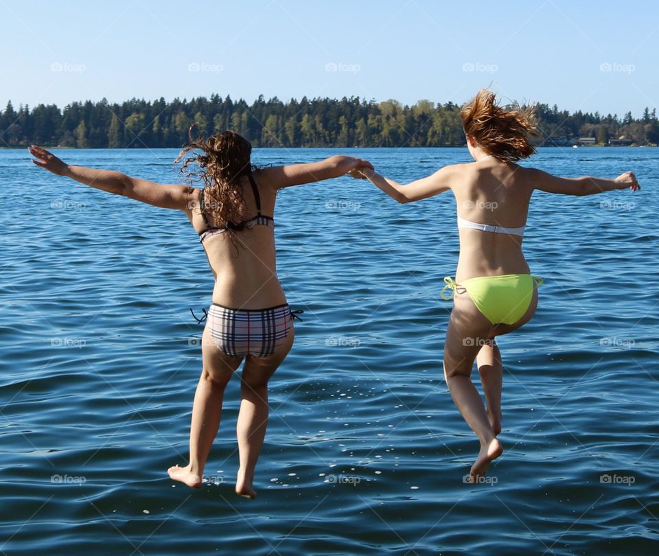 Two young women take advantage of a perfect Summer day, jumping into the clean, blue waters of American Lake in Tillicum, Washington