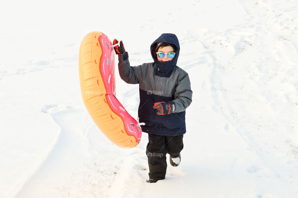 Young boy having fun with a snow tube