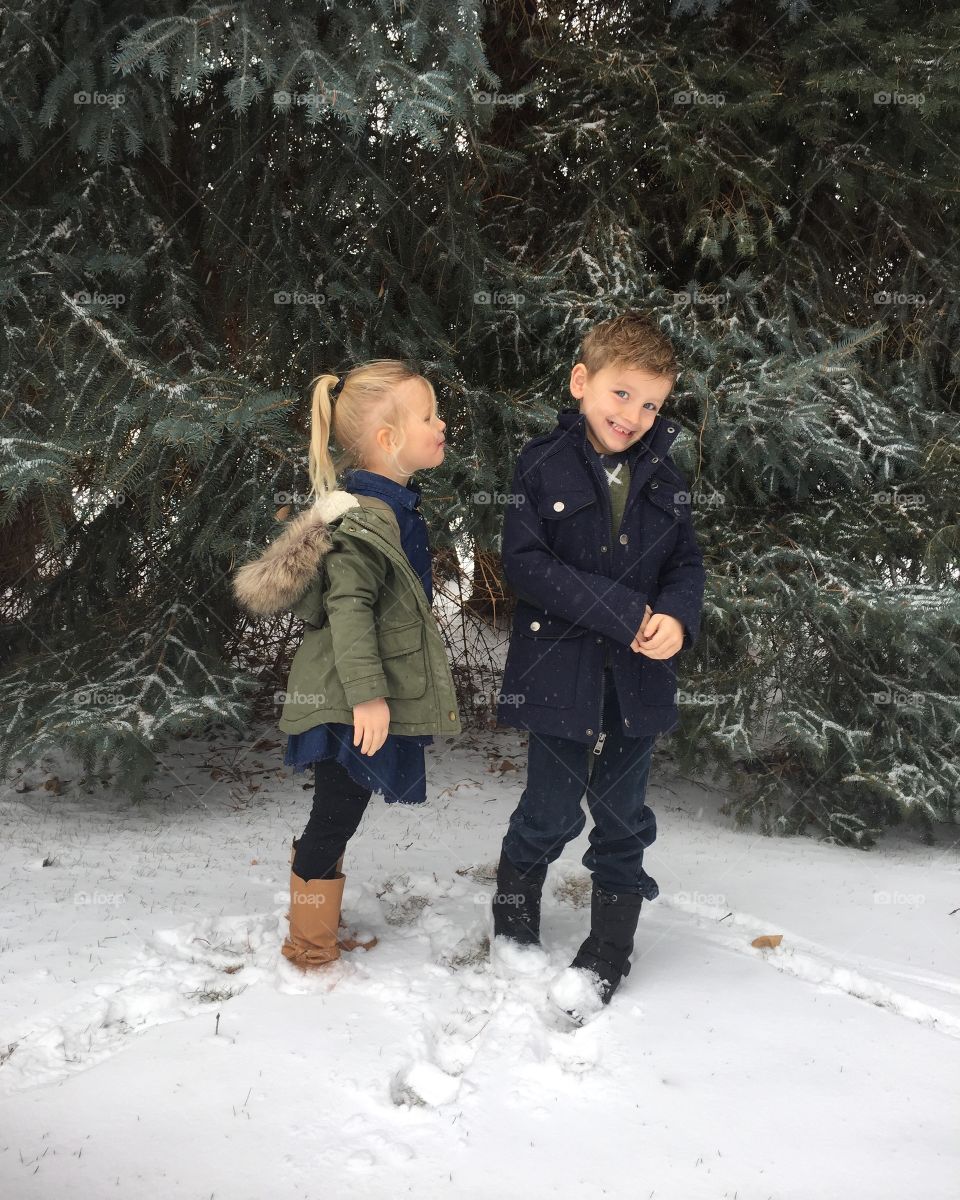 Brother and sister standing snow near trees