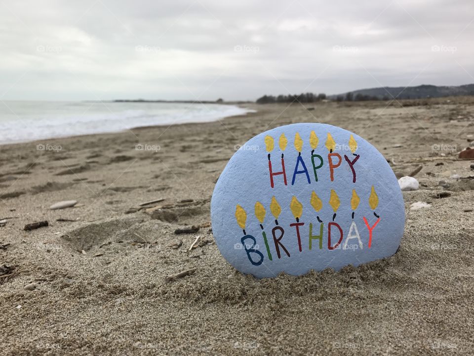Happy Birthday message on a carved and painted stone on the beach 