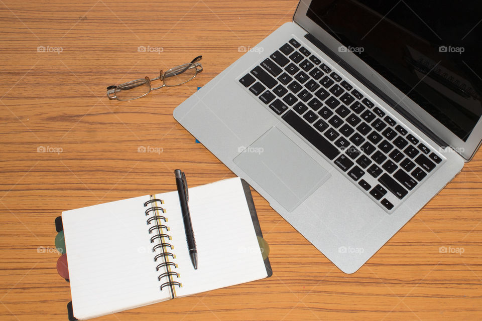 Desk with open notebook, mobile phone, eye glasses, placed on office table. Top view with copy space. Business still life concept with office stuff on table. Education, working or planning concept