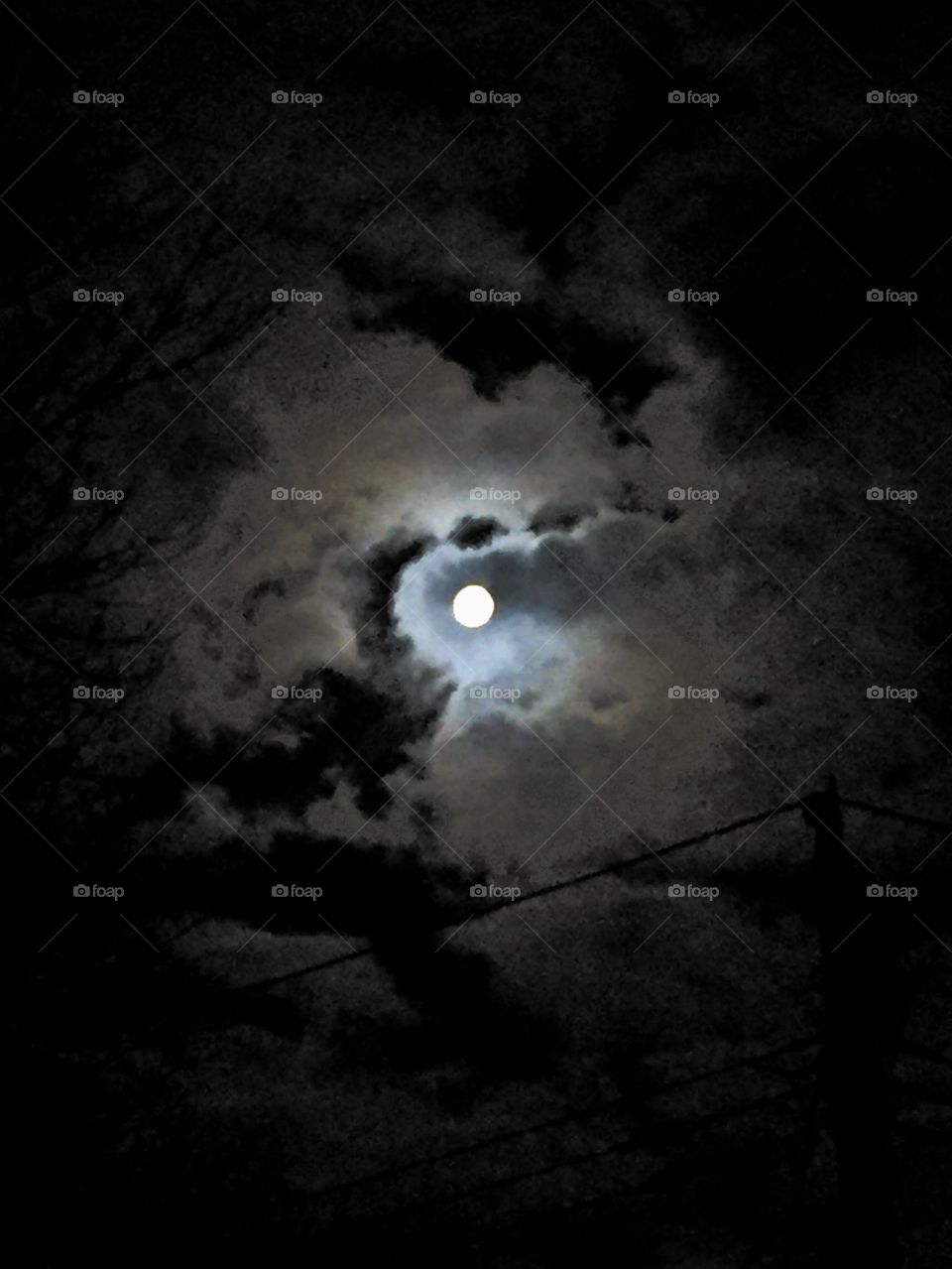 Full moon surrounded by clouds.