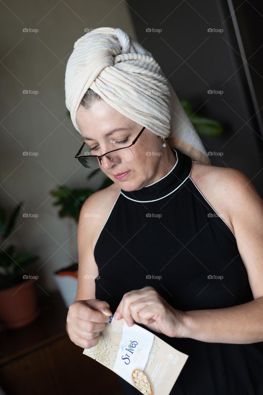 Aged woman with a cosmetics product in her hands, face mask brand St. Ives. Personal care