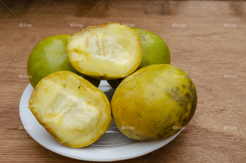 White Plate Filled With Cut And Whole White Sapote Fruits