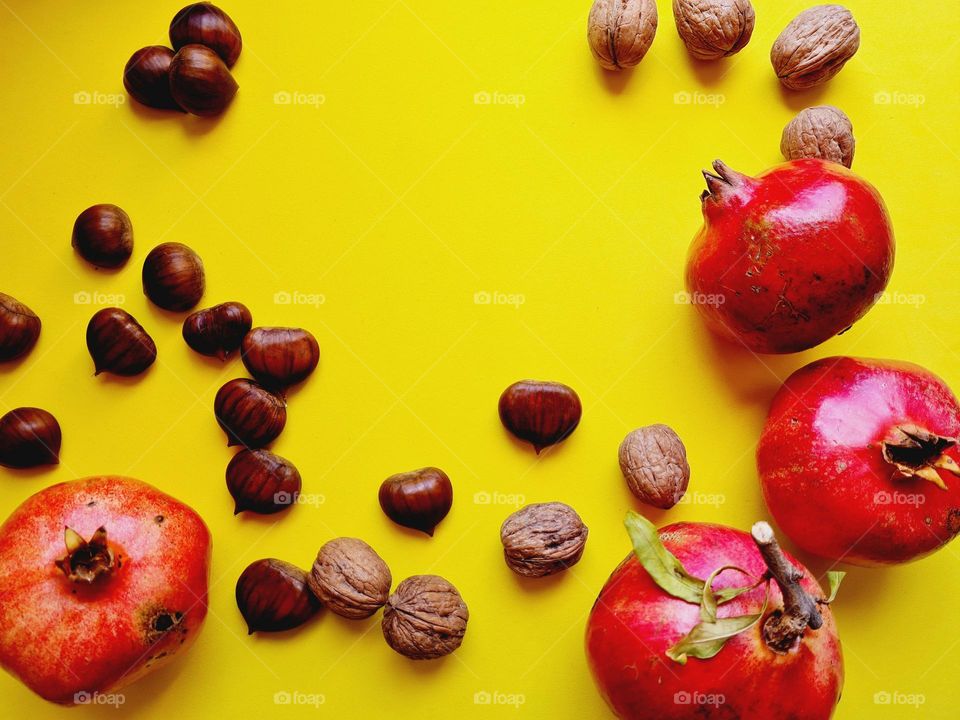 healthy food: pomegranates and dried fruits on yellow background