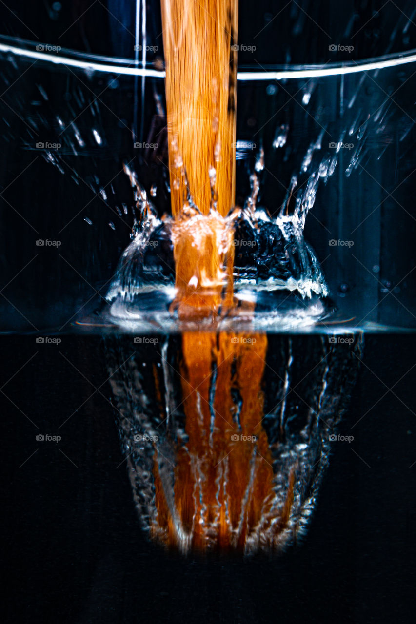 close-up of wooden pestle falling into water