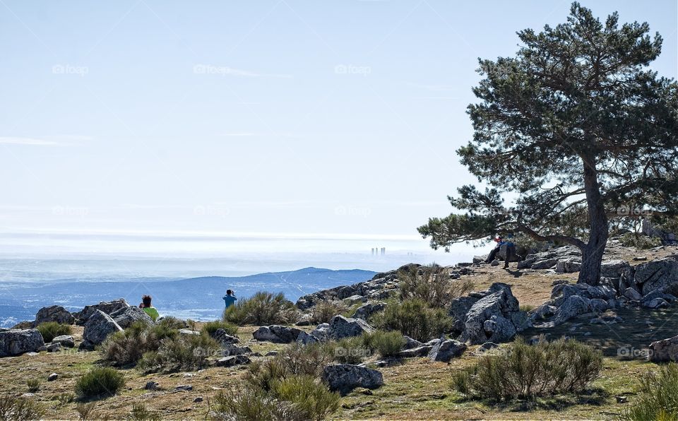 People enjoying the view of Madrid in the mist from the top of a mountain 