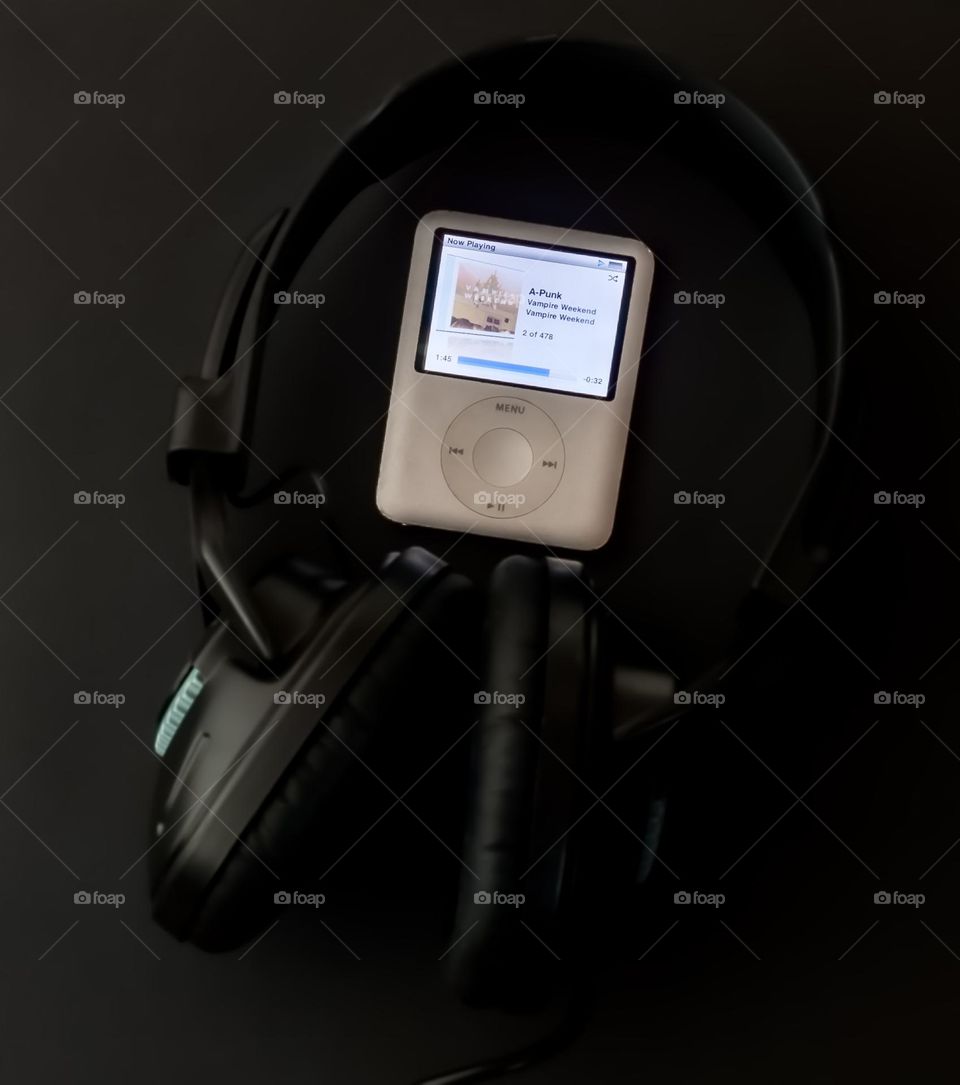 Apple iPod with headphones on black background 