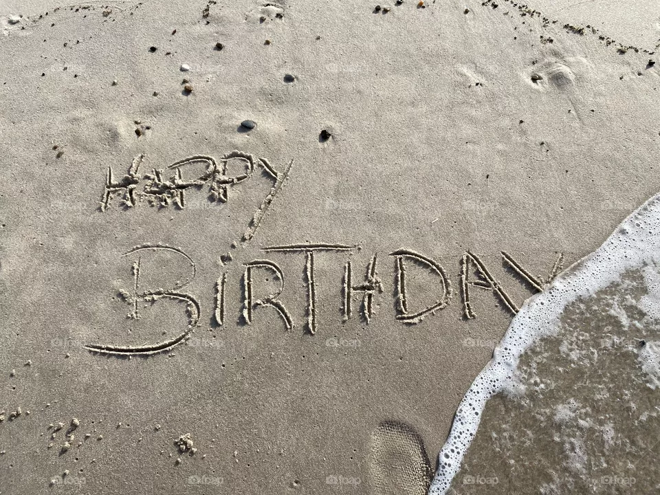 Geburtstagsgruß auf Sand geschrieben an der Brandung der Nordsee/ Birthday greeting written on sand on the surf of the North Sea