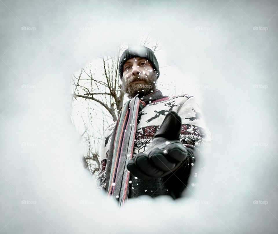 Man in winter wear seen through a snowy hole