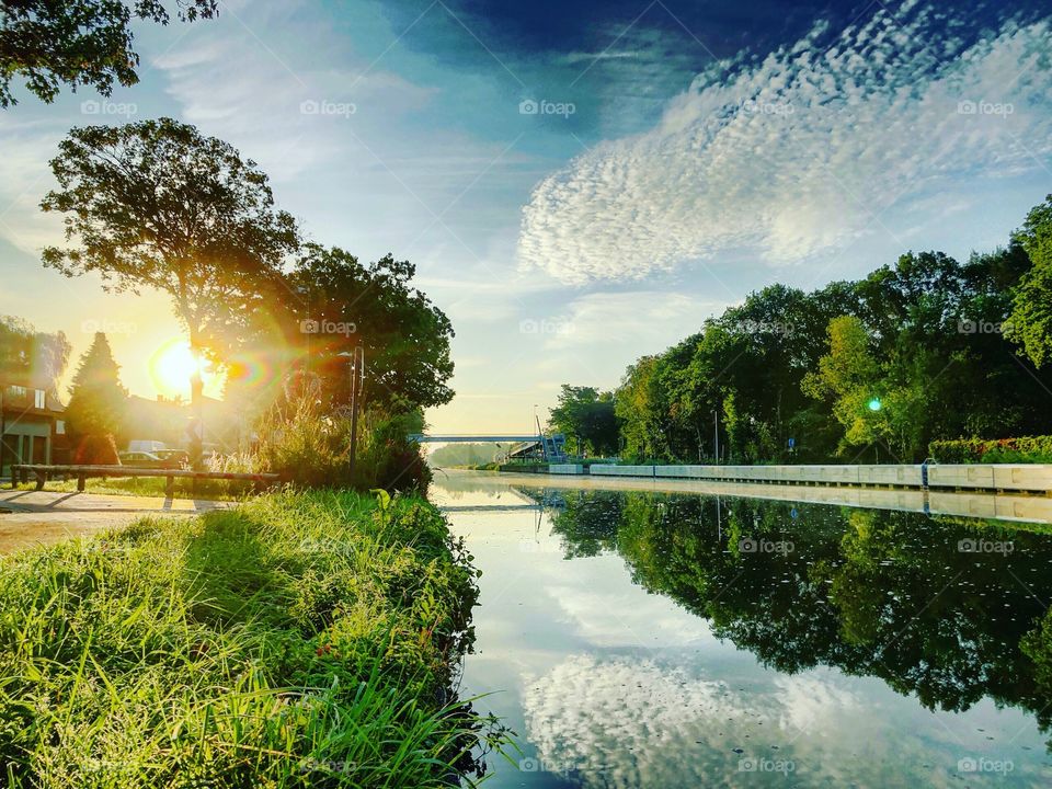 Fluffy clouds at sunrise reflected in the water of the river 