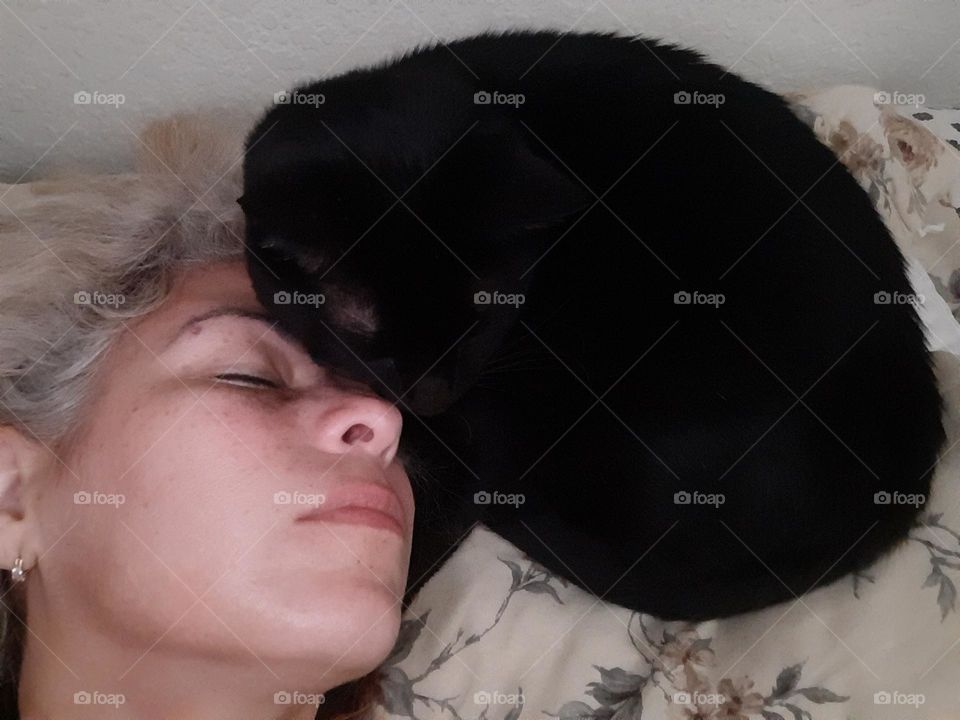 Human and cat resting facing each other.