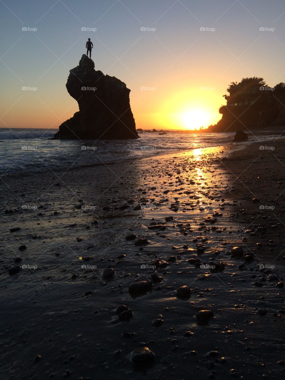 Bro on a rock at sunset on the beach. 