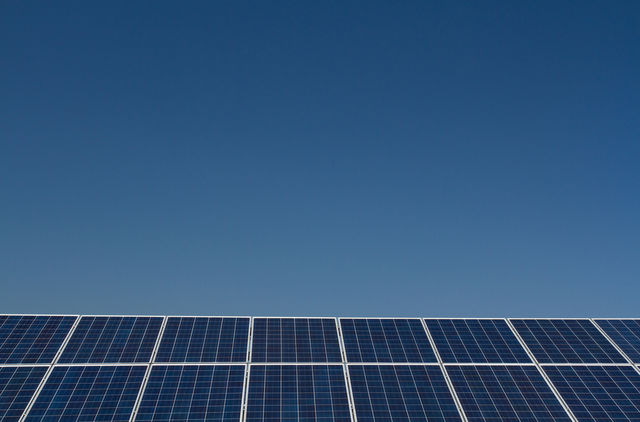 A row of solar panels generating clean electricity under a clear blue sky.