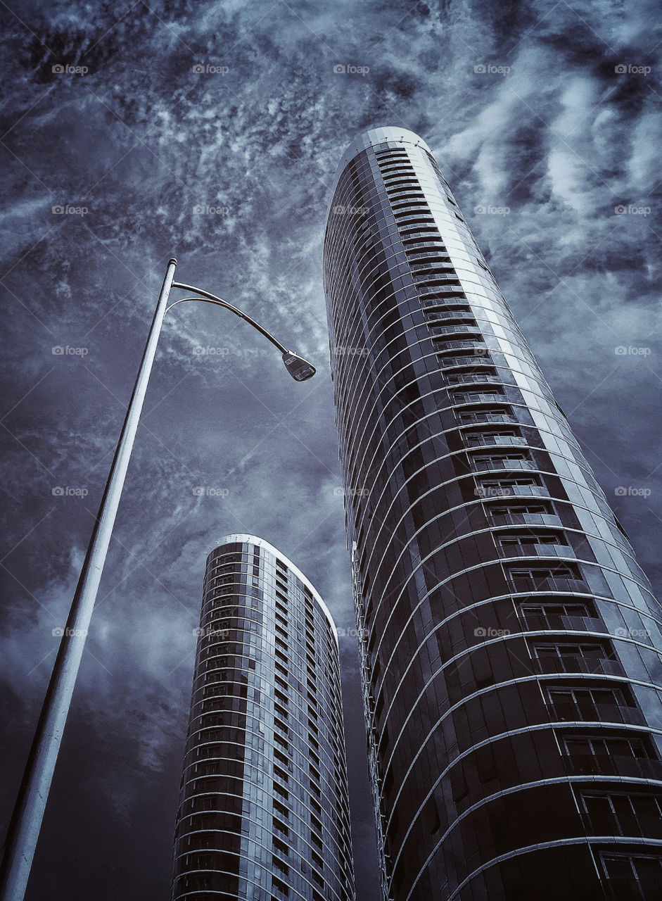 Looking up at modern skyscrapers against a cloudy sky