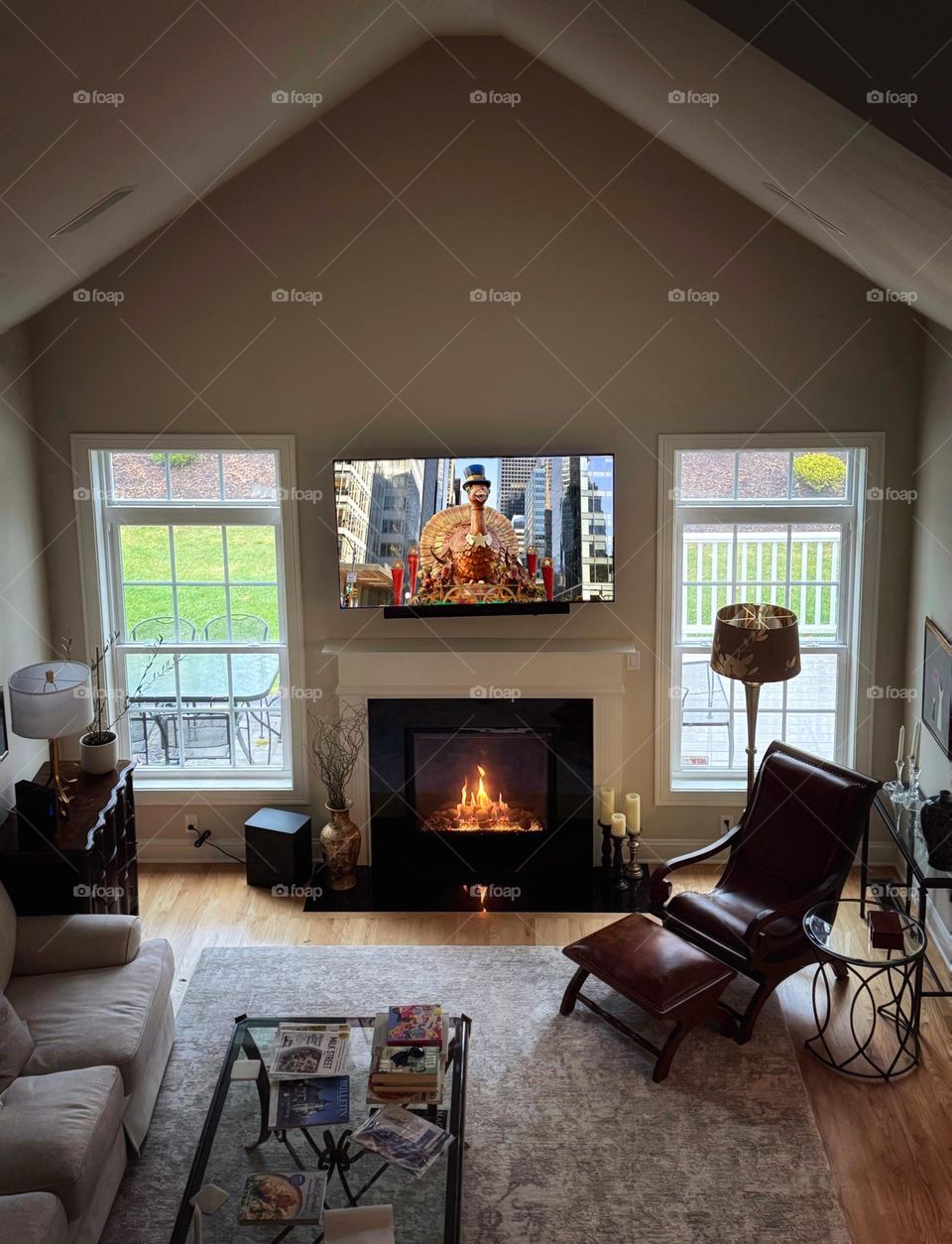An empty room on Thanksgiving morning with a fire in the fireplace and the Macy’s Thanksgiving Day Parade on the flat-screen TV