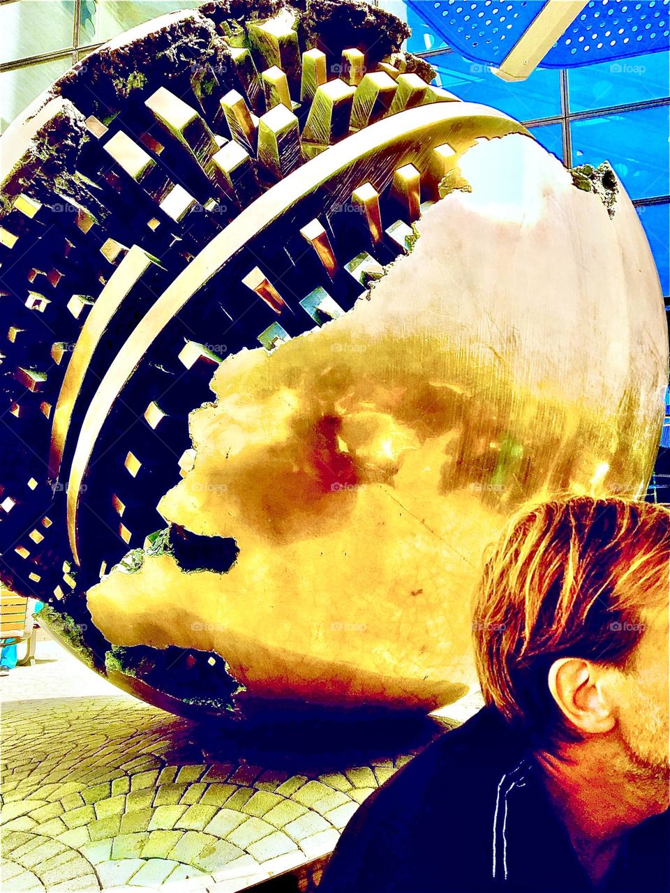 Timothy is in the atrium at Mt Sinai hospital on the Upper East Side of Manhattan in NYC. This sculpture of a gigantic golden sphere reminds of a broken Christmas ornament that reveals gears like those of a watch inside. 2020. Hypnotic Productions