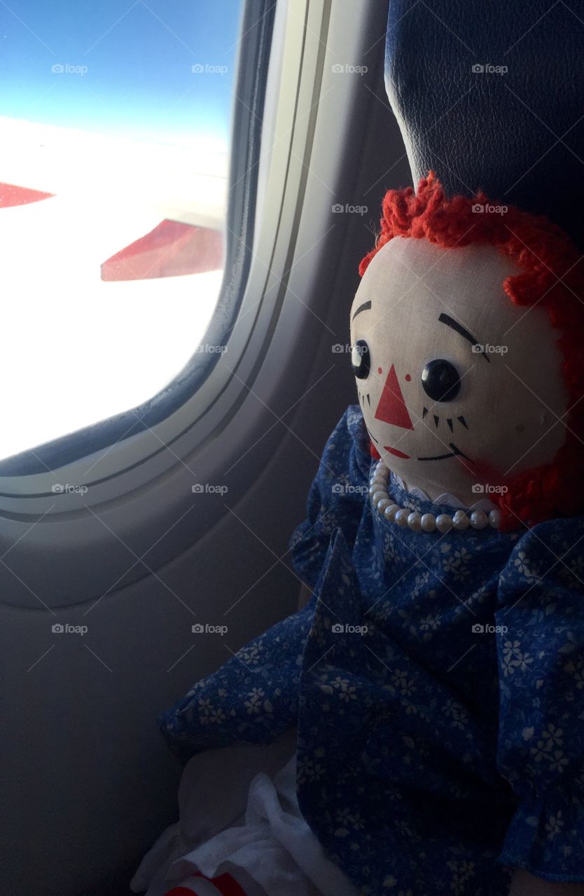 Raggedy Ann looking out plane window