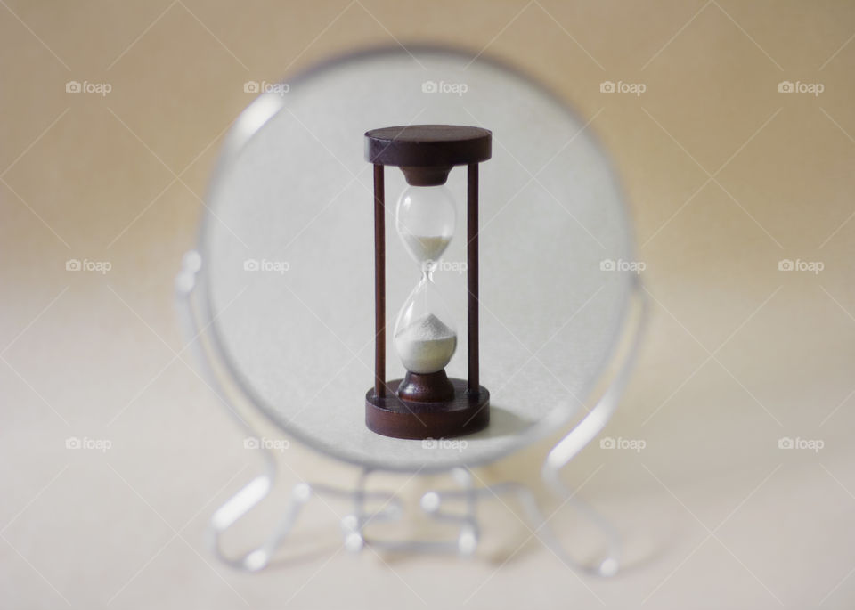 Life time. Reflection of a hourglass in the round mirror