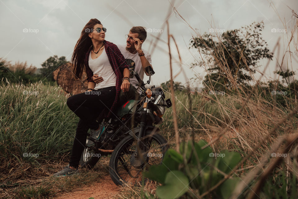 a guy and a girl are sitting near a motorcycle