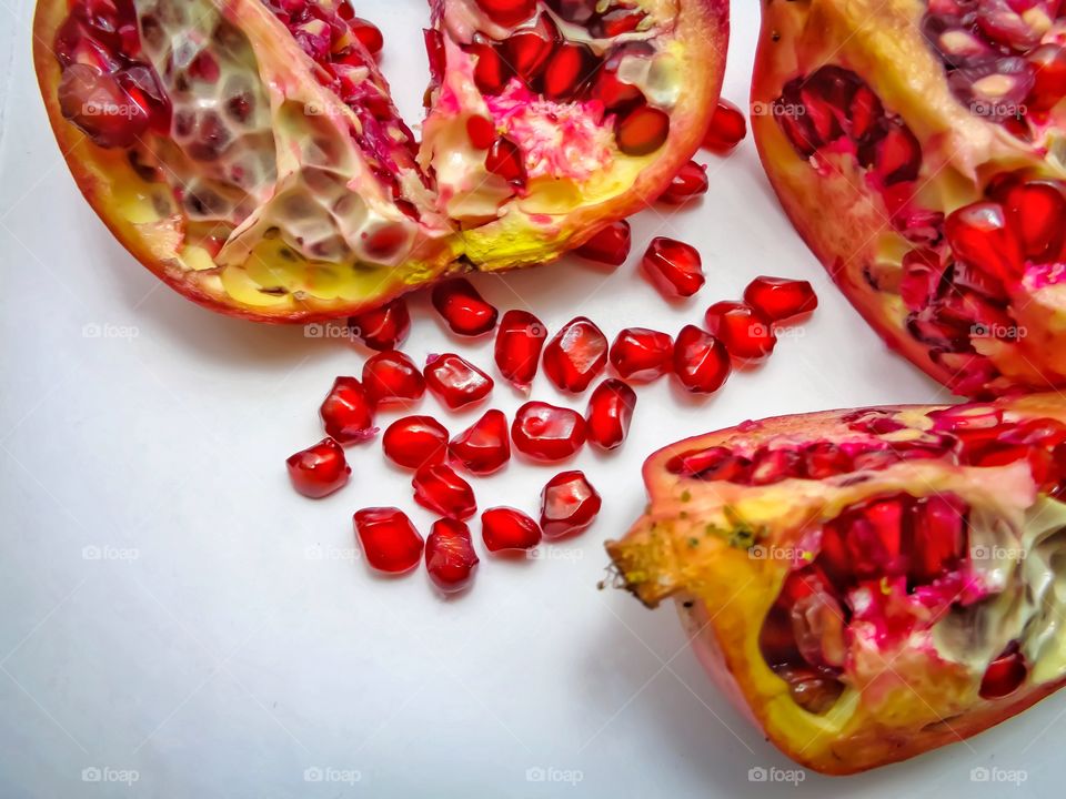 Pomegranate and red seeds on white background