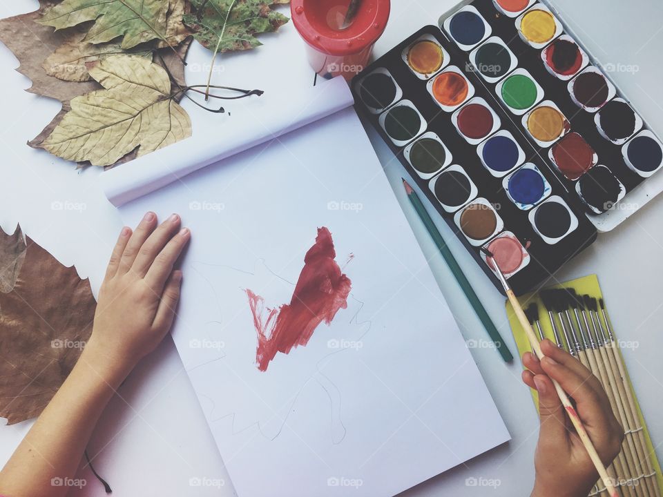 A child painting an autumn leaf