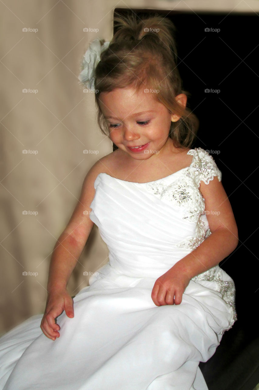 Little girl in white dress sitting in chair