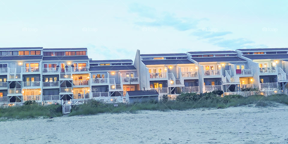 row of condos lit up against evening sky on nc beach.