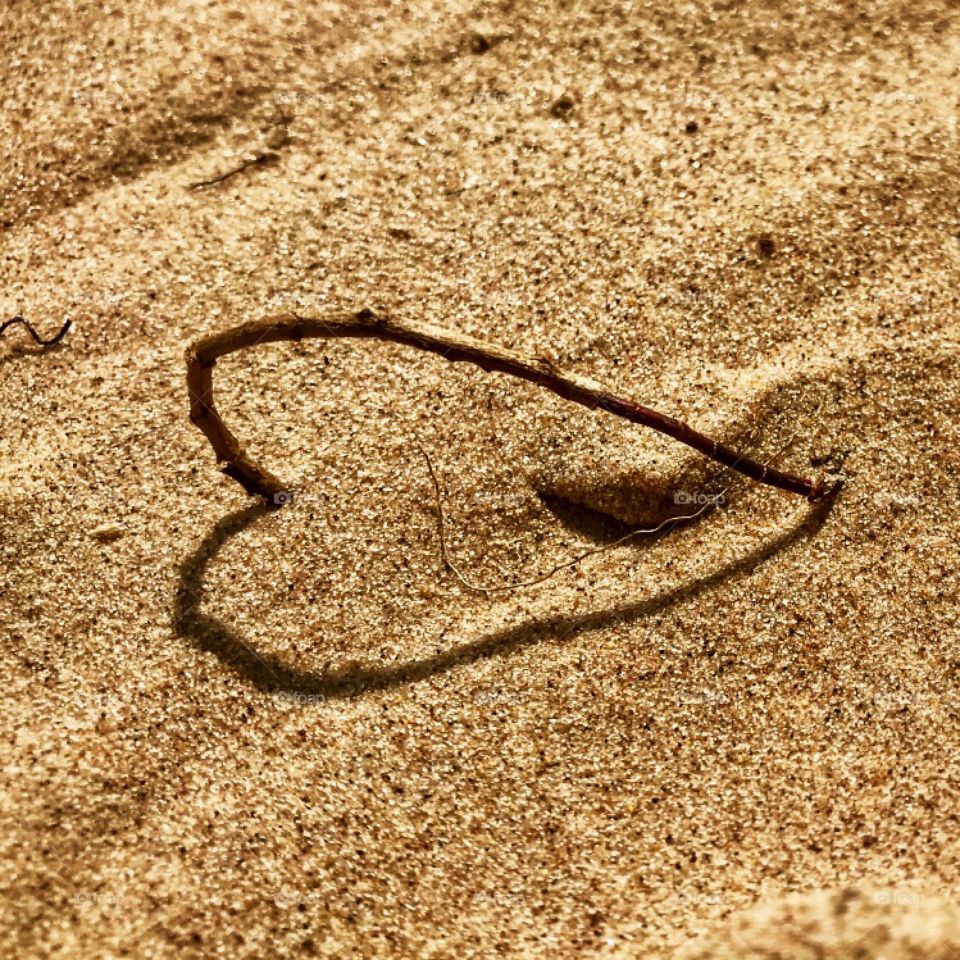 A twig in the sand and its shadow forming a heart—taken in Ludington, Michigan 