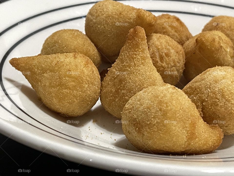 Coxinha: popular food in Brasil consisting of chopped or shredded chicken meat, covered in dough, molded into a shape resembling a teardrop, battered and fried. Very common in parties. Delicious!