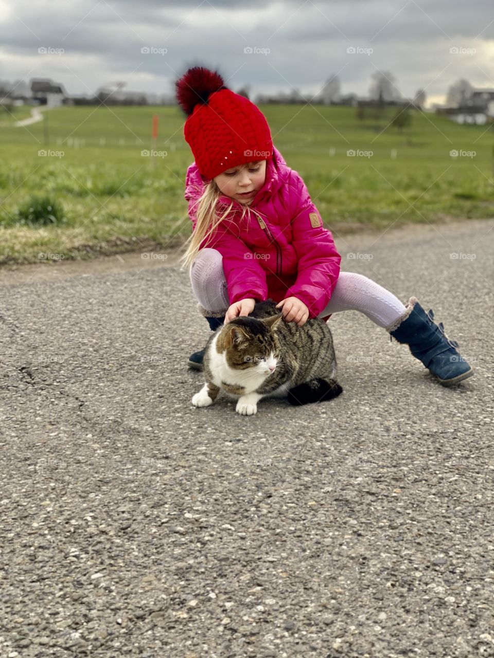 the cat sits on the grass, the girl hugs the cat