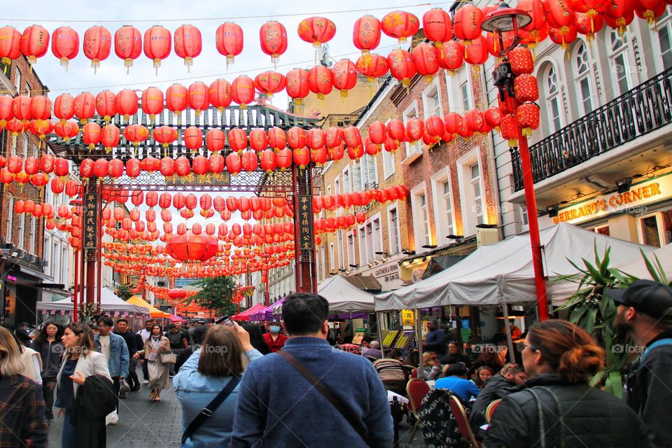 Crowds walk down a street decorated with red Chinese balloons