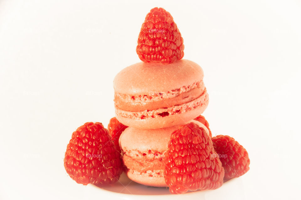 two pink macarons and raspberries