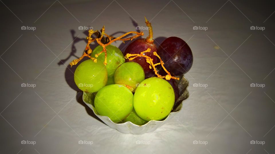 a small bowl of seedless green and brown grapes