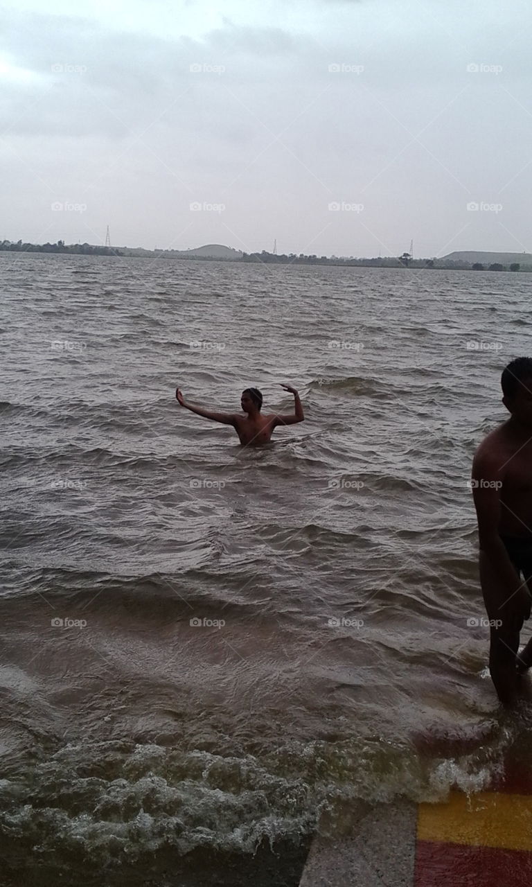 A shirtless man stretching his arm in sea