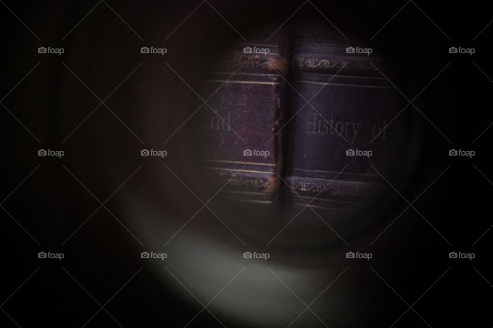The view of an old history books’ bindings through a spyglass.