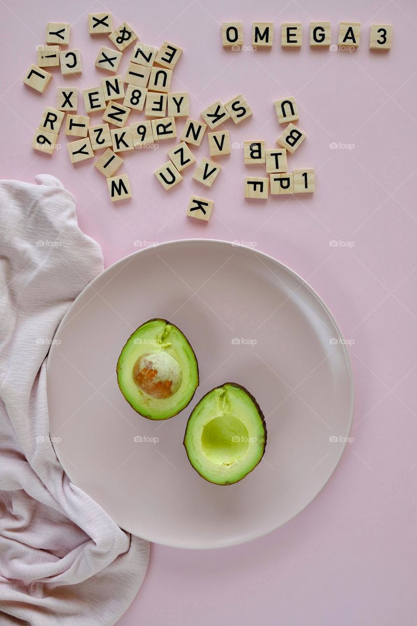 Directly above view of parts of avocado on pink plate isolated on pink background.