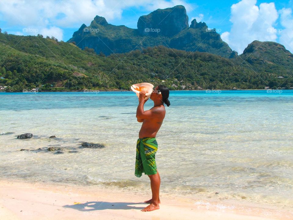 Blowing a conch in Bora Bora. Blowing a conch shell at the Sofitel private Island in Bora Bora, French Polynesia