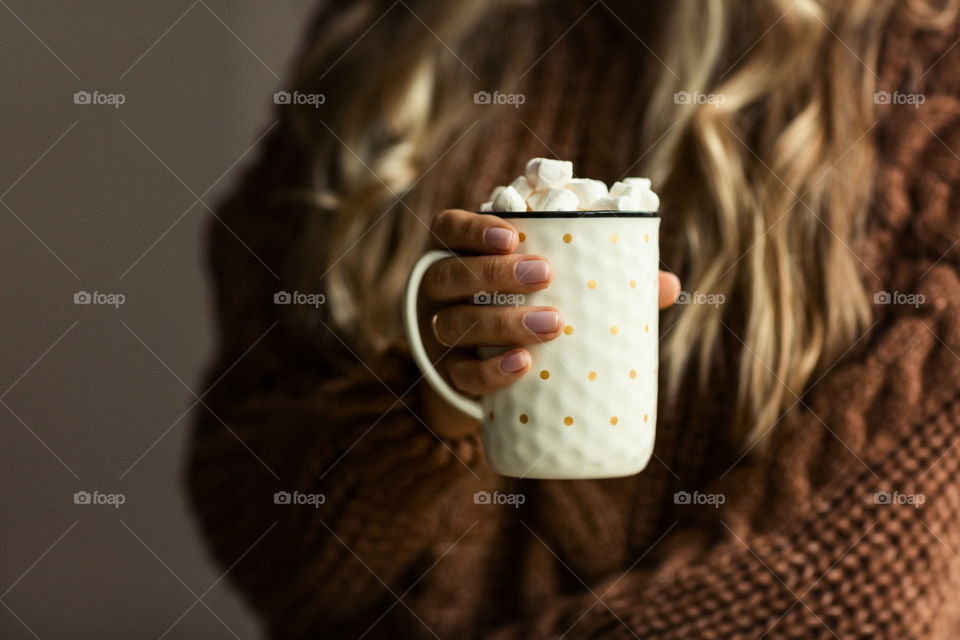 Female hand holding cup of coffee with marshmallow 