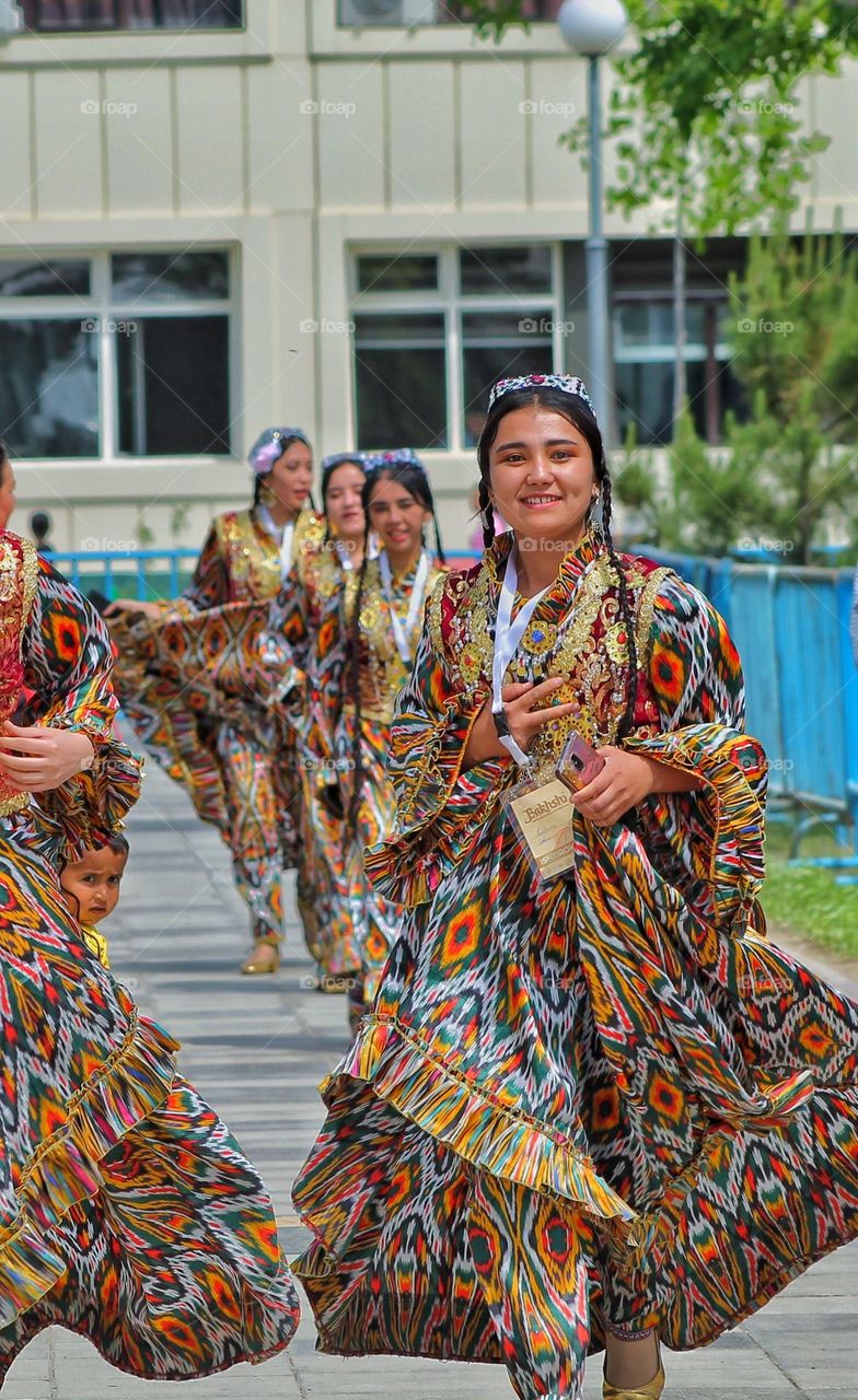 a happy girl runs to the stage in a national Asian costume dress