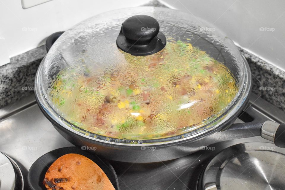 Homecooking cooking Frittata at home and adding and mixing ingredients and removing the Frittata from the pan for cutting and serving on a white plate with tomatoes. Healthy home cooking in kitchen. Breakfast and lunch food preparation.