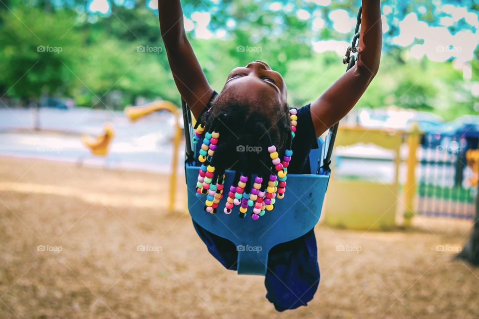Little girl having fun on a swing at a park