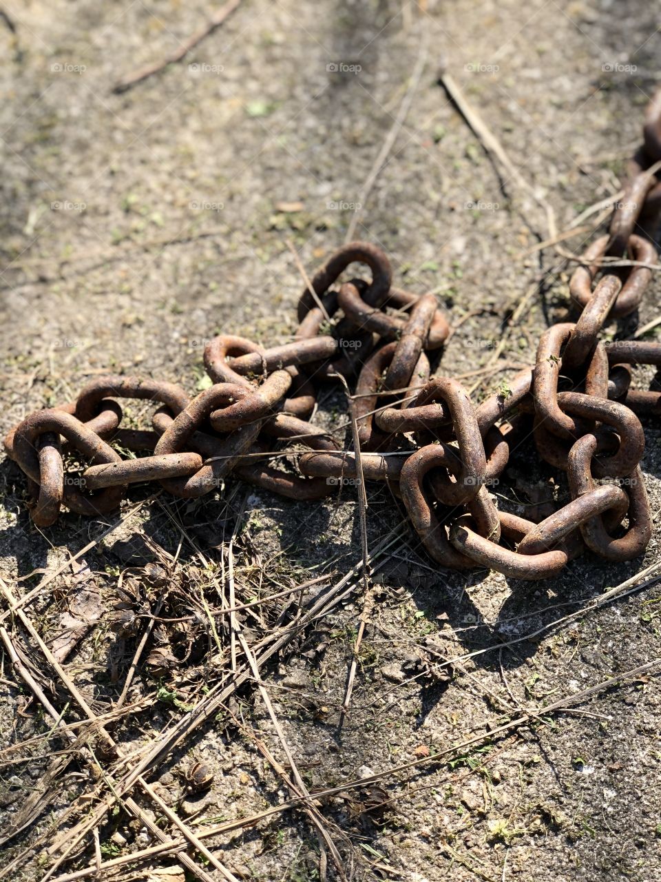 Closeup of heavy towing chain covered in rust and discarded 